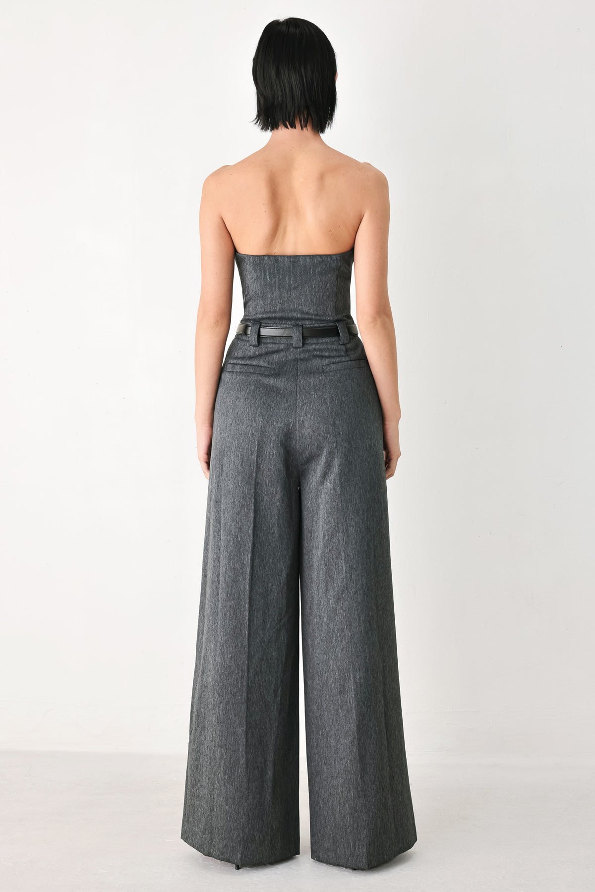 A model wearing a dark gray strapless wide-leg jumpsuit with a matching belt | FREEMARKET