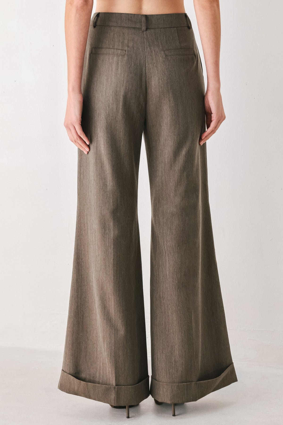 Woman wearing brown tailored flared pants with a big cuff at the bottom | FREEMARKET