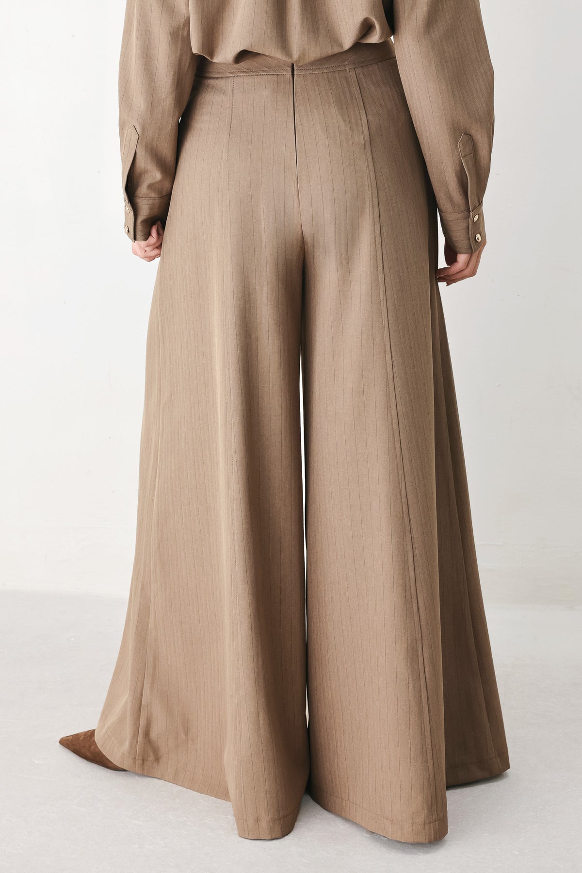 A person wearing high-waisted, wide-leg trousers in a warm taupe-brown color | FREEMARKET