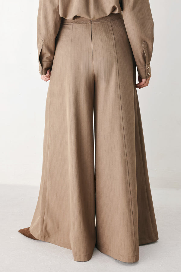 A person wearing high-waisted, wide-leg trousers in a warm taupe-brown color | FREEMARKET