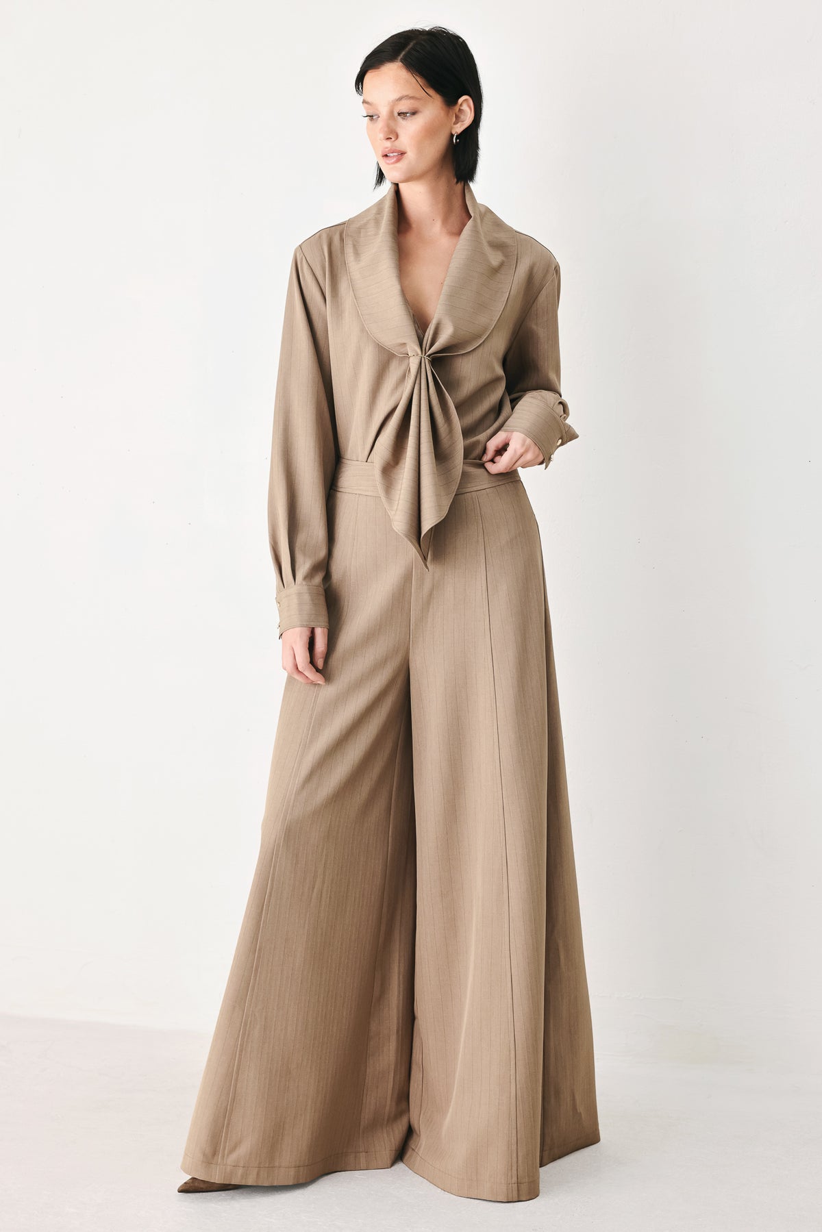 A person wearing high-waisted, wide-leg trousers in a warm taupe-brown color | FREEMARKET