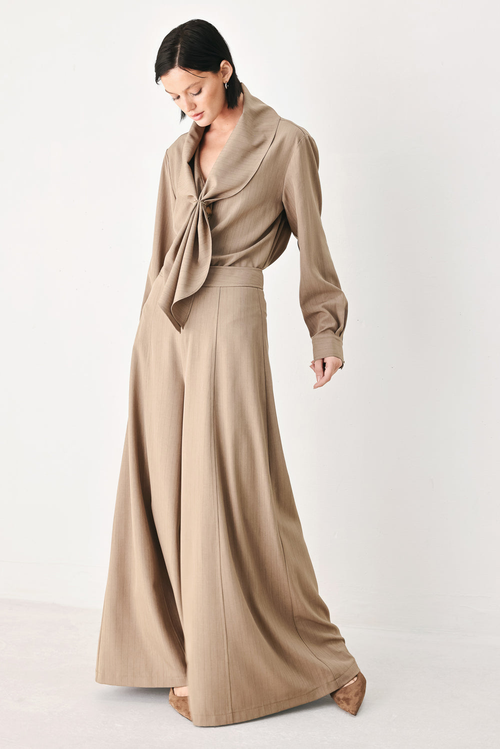 A person wearing high-waisted, wide-leg trousers in a warm taupe-brown color | FREEMARKET