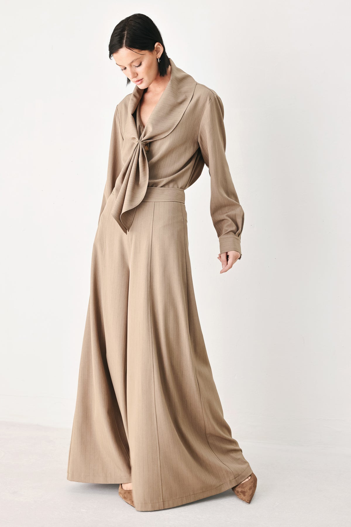 A person wearing high-waisted, wide-leg trousers in a warm taupe-brown color | FREEMARKET
