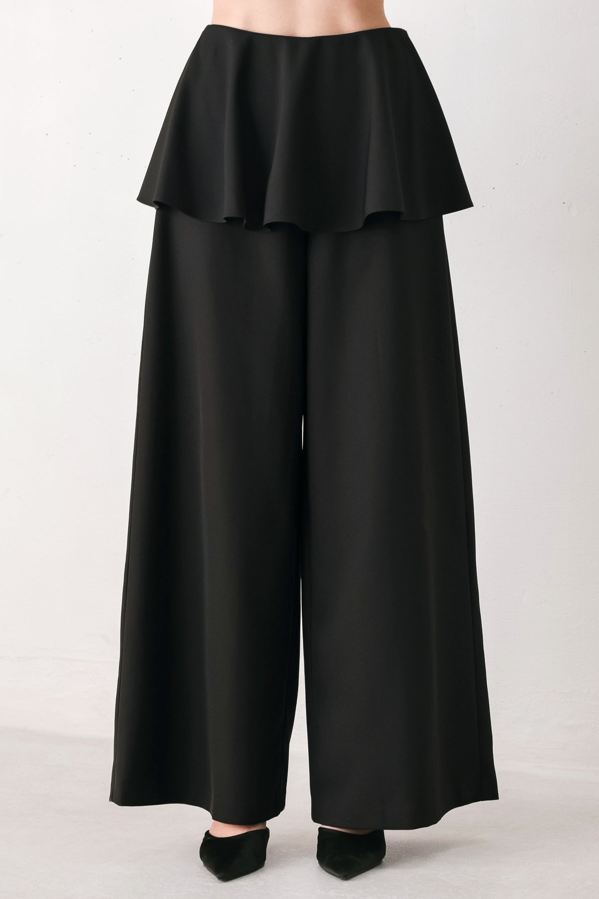 Black wide-leg pants with a dramatic layered ruffle waistband, shown on a model | FREEMARKET