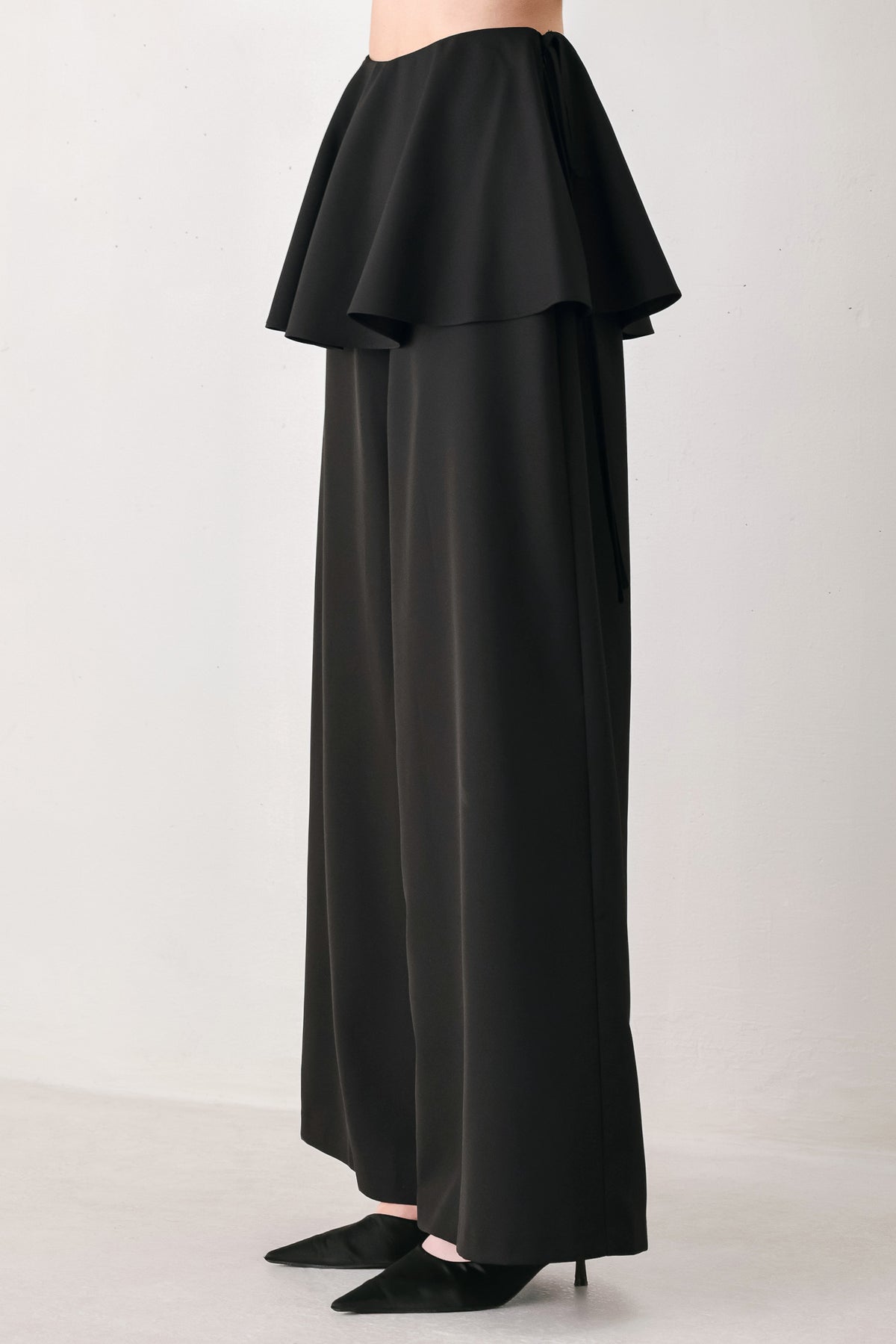 Black wide-leg pants with a dramatic layered ruffle waistband, shown on a model | FREEMARKET