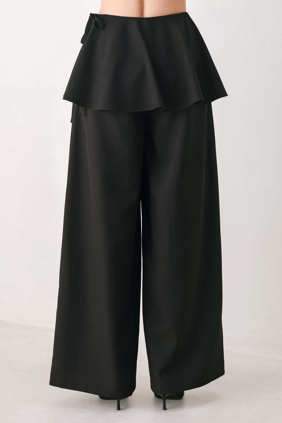 Black wide-leg pants with a dramatic layered ruffle waistband, shown on a model | FREEMARKET