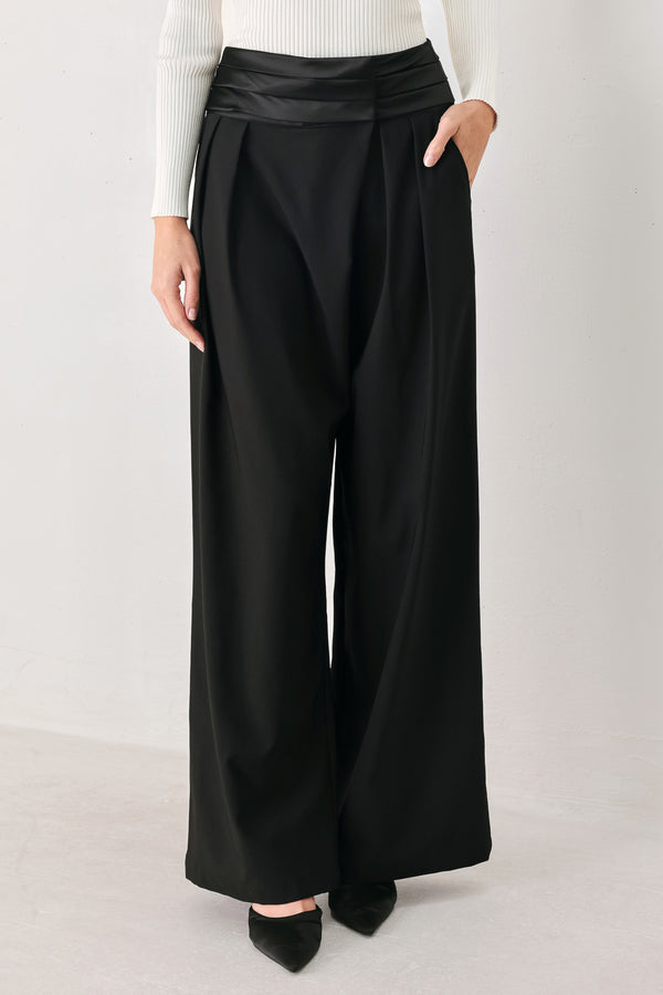 A model wearing high-waisted, wide-leg black trousers with a satin-like waistband | FREEMARKET