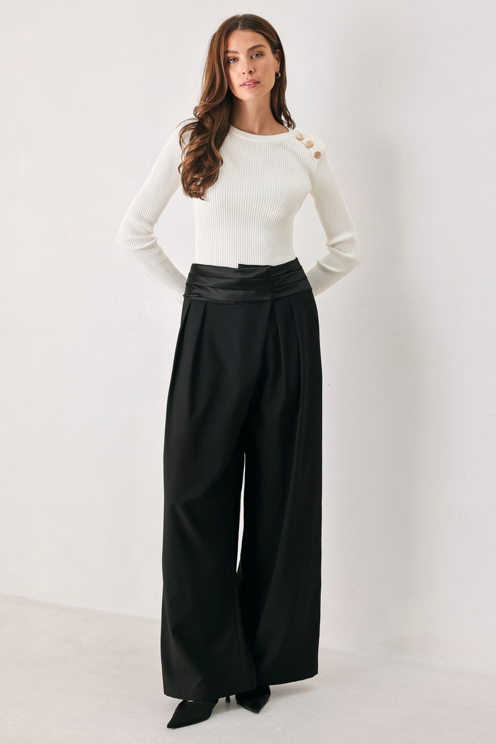 A model wearing high-waisted, wide-leg black trousers with a satin-like waistband | FREEMARKET