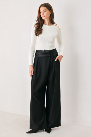 A model wearing high-waisted, wide-leg black trousers with a satin-like waistband | FREEMARKET