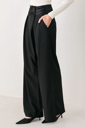 A model wearing high-waisted, wide-leg black trousers with a satin-like waistband | FREEMARKET