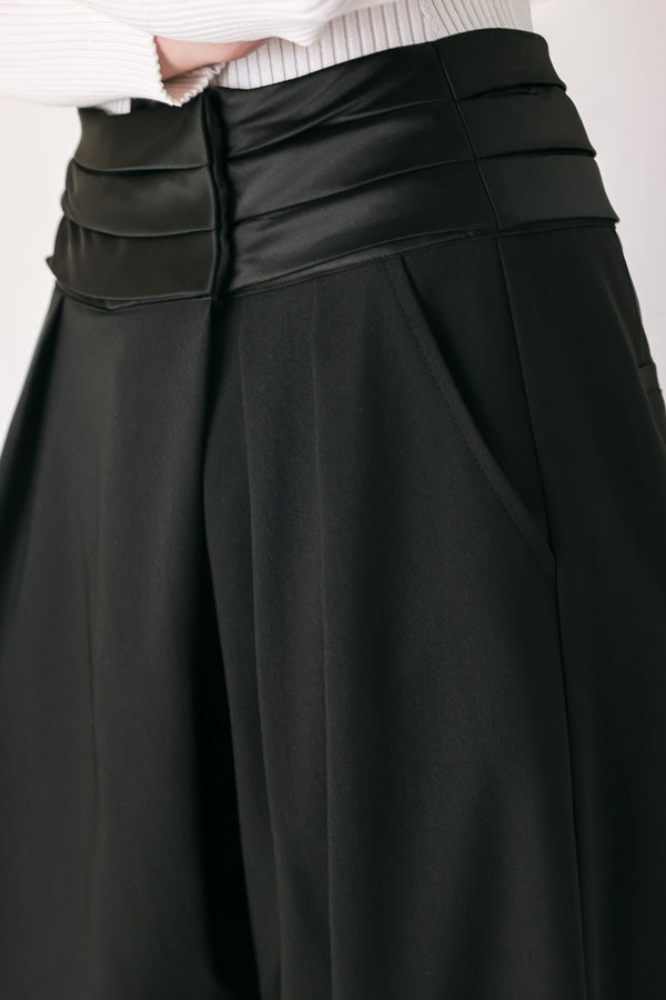 A model wearing high-waisted, wide-leg black trousers with a satin-like waistband | FREEMARKET
