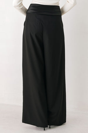 A model wearing high-waisted, wide-leg black trousers with a satin-like waistband | FREEMARKET