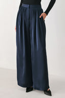 Woman wearing a navy blue satin pants with pleats | FREEMARKET