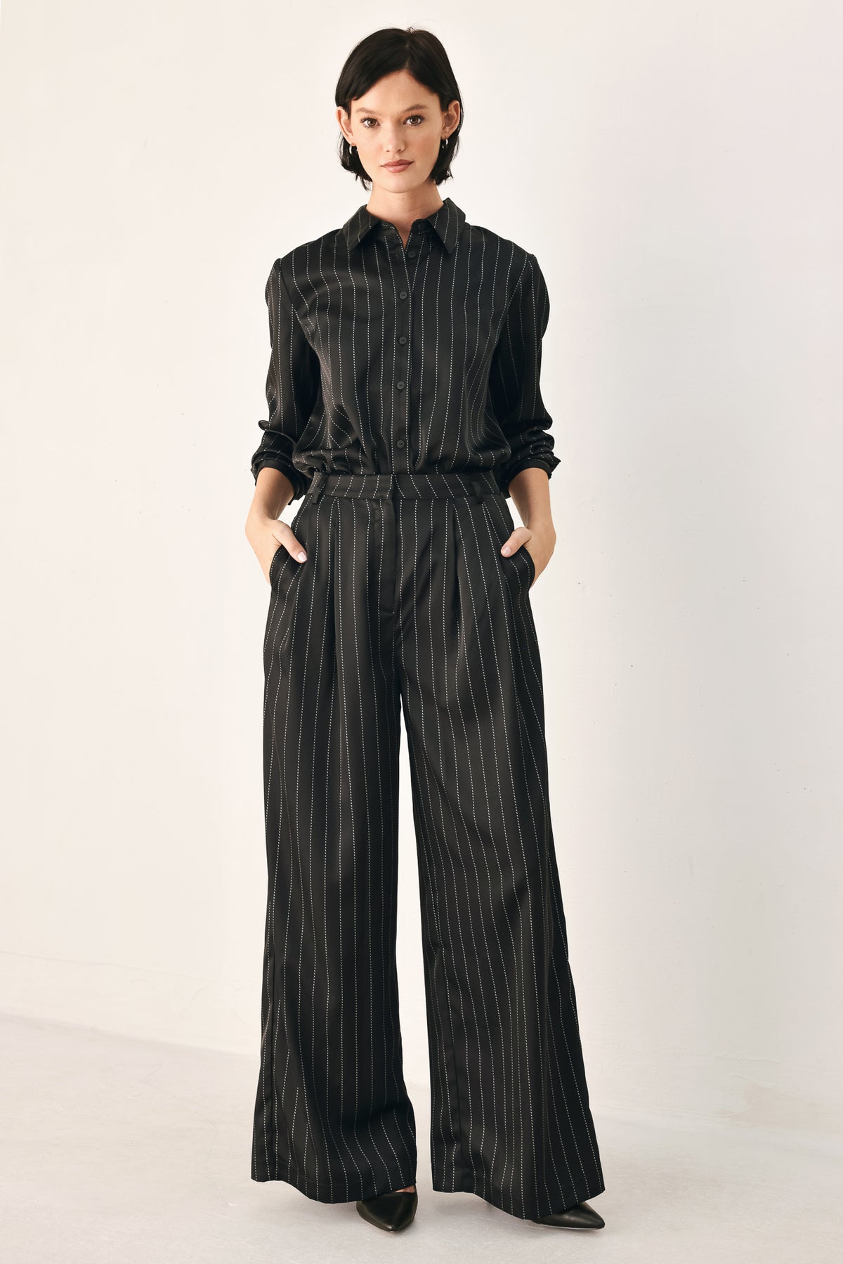 Black wide-leg trousers with thin white vertical pinstripes, shown on a model | FREEMARKET