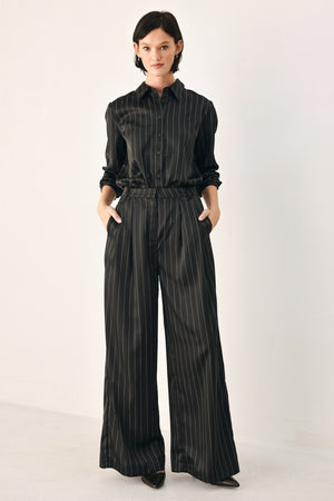 Black wide-leg trousers with thin white vertical pinstripes, shown on a model | FREEMARKET