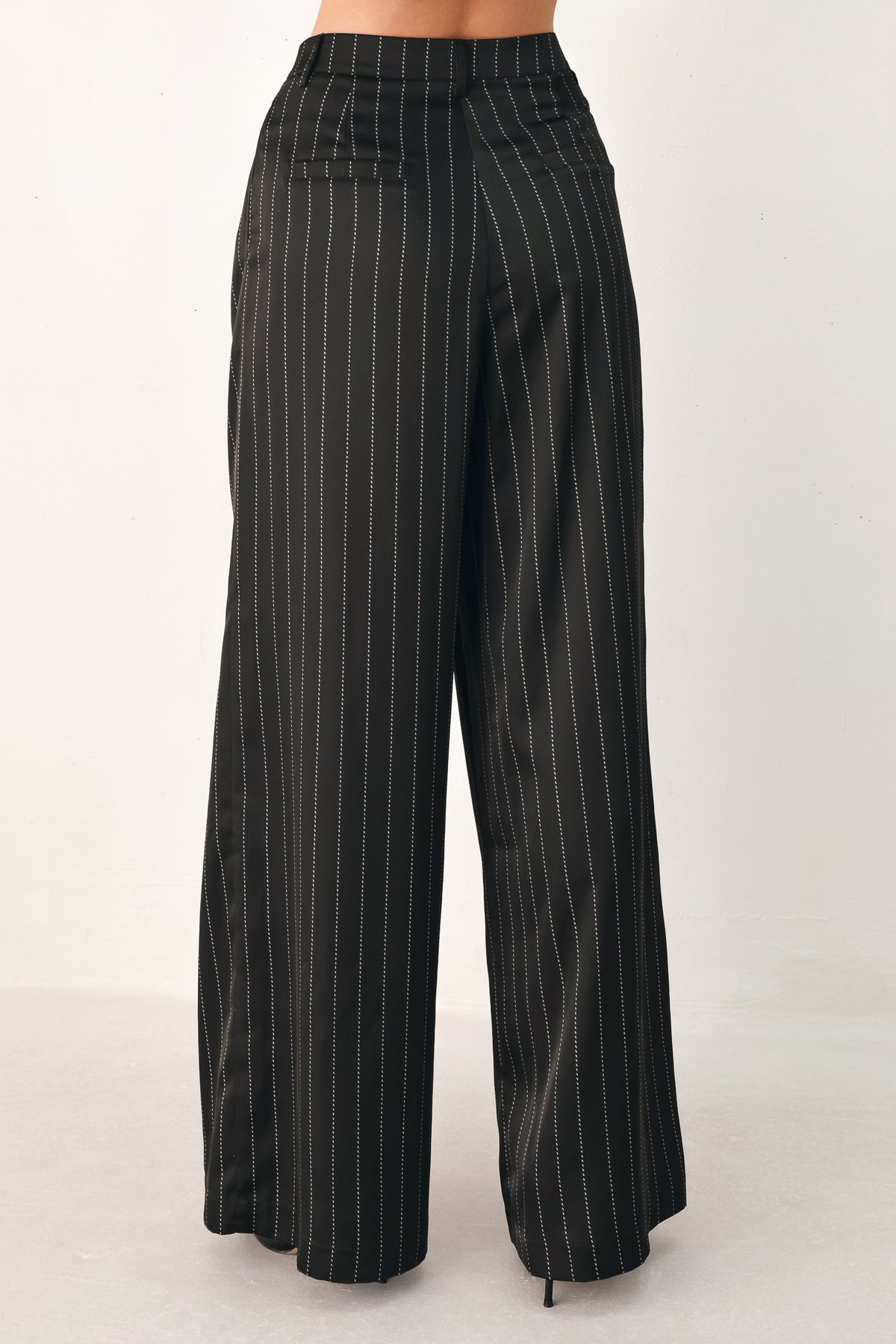 Black wide-leg trousers with thin white vertical pinstripes, shown on a model | FREEMARKET
