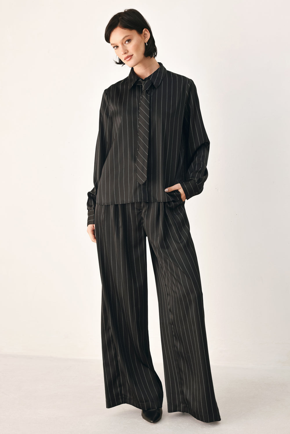 Black wide-leg trousers with thin white vertical pinstripes, shown on a model | FREEMARKET