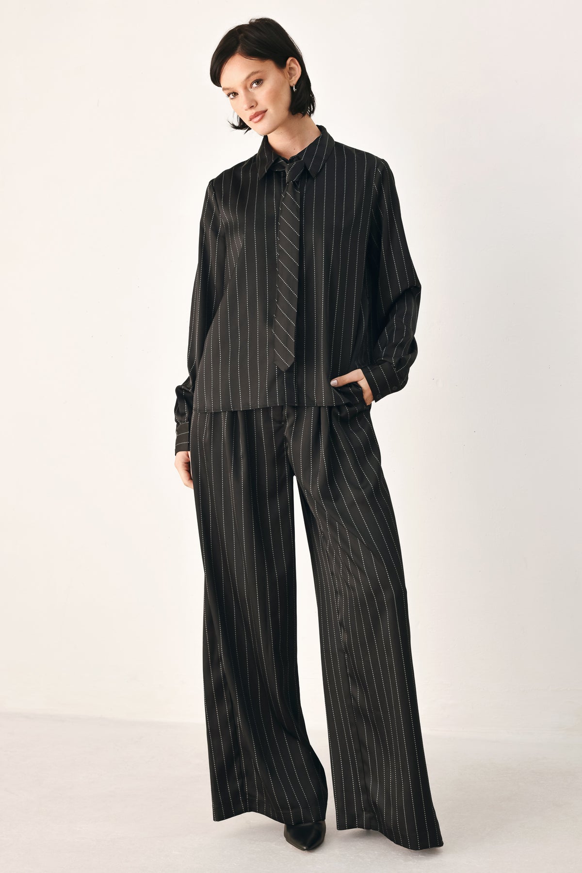 Black wide-leg trousers with thin white vertical pinstripes, shown on a model | FREEMARKET
