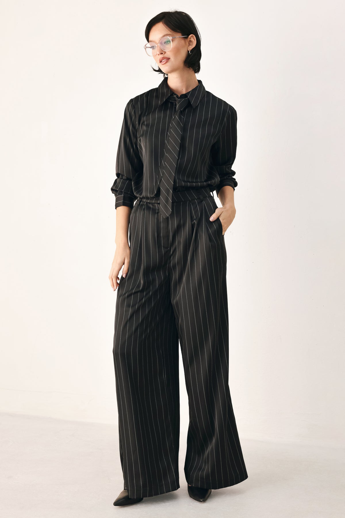 Black wide-leg trousers with thin white vertical pinstripes, shown on a model | FREEMARKET