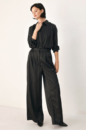 Black wide-leg trousers with thin white vertical pinstripes, shown on a model | FREEMARKET