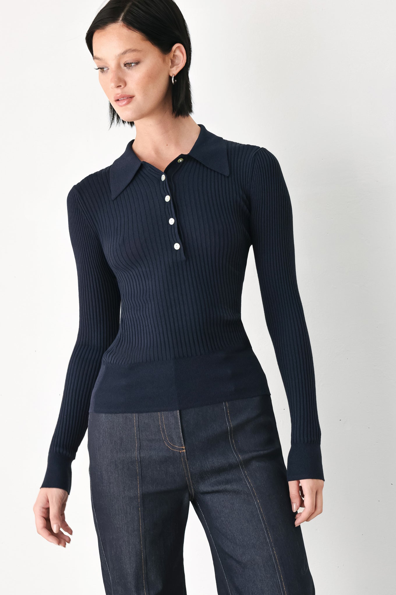 A woman wearing a navy blue ribbed long-sleeve polo-neck knit top | FREEMARKET