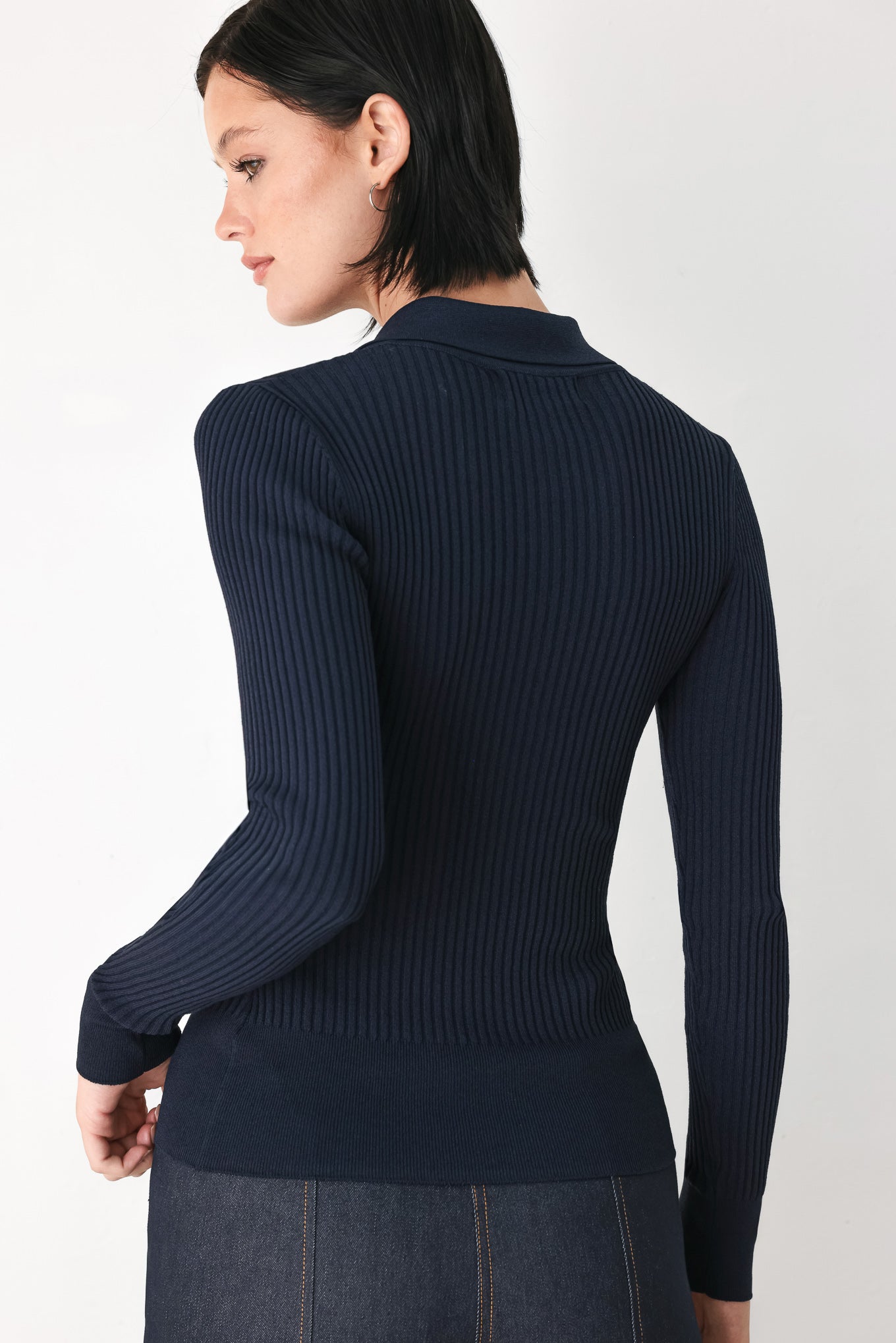 A woman wearing a navy blue ribbed long-sleeve polo-neck knit top | FREEMARKET