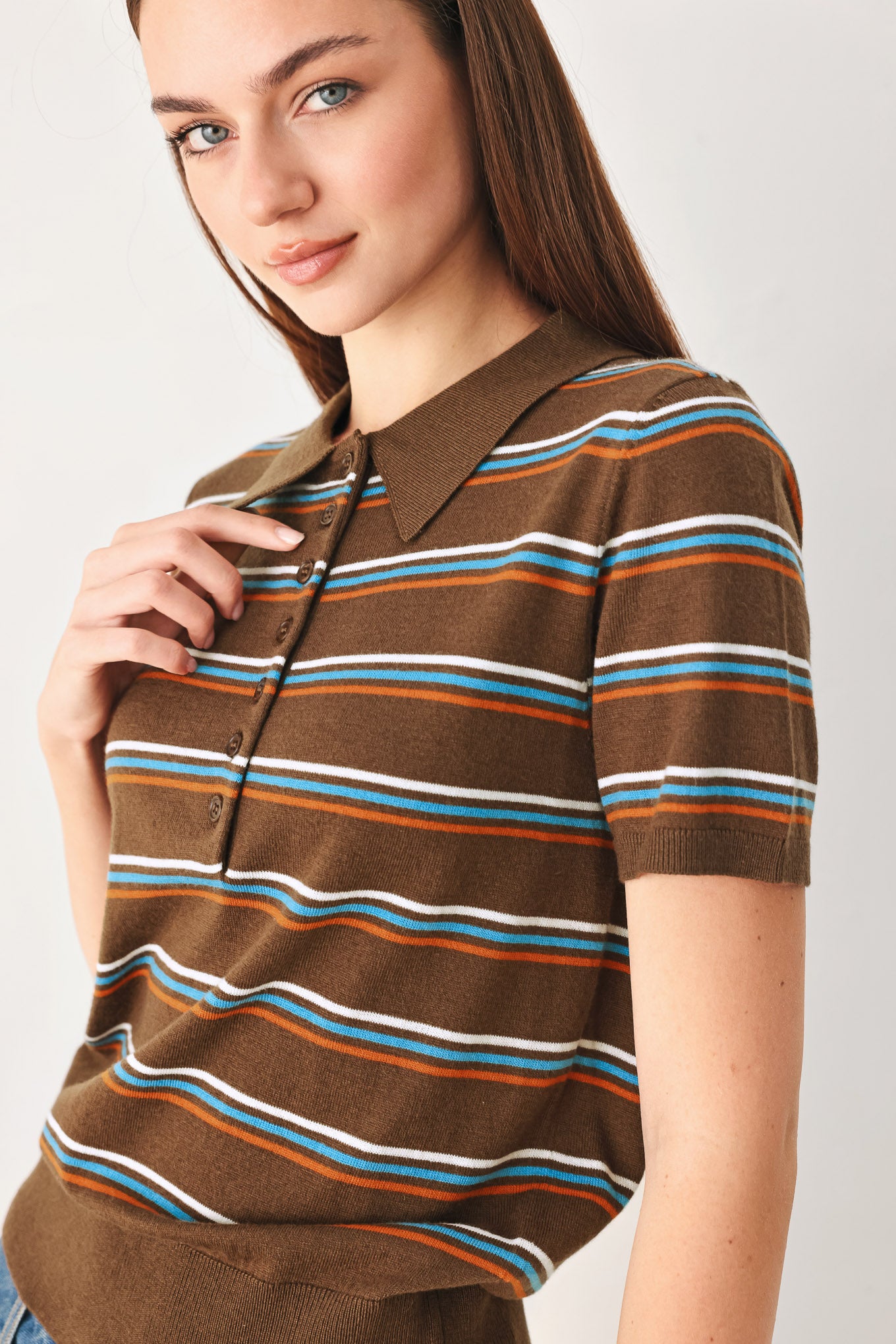 A woman wearing a brown short-sleeve polo shirt with horizontal stripes in white, blue, and orange | FREEMARKET