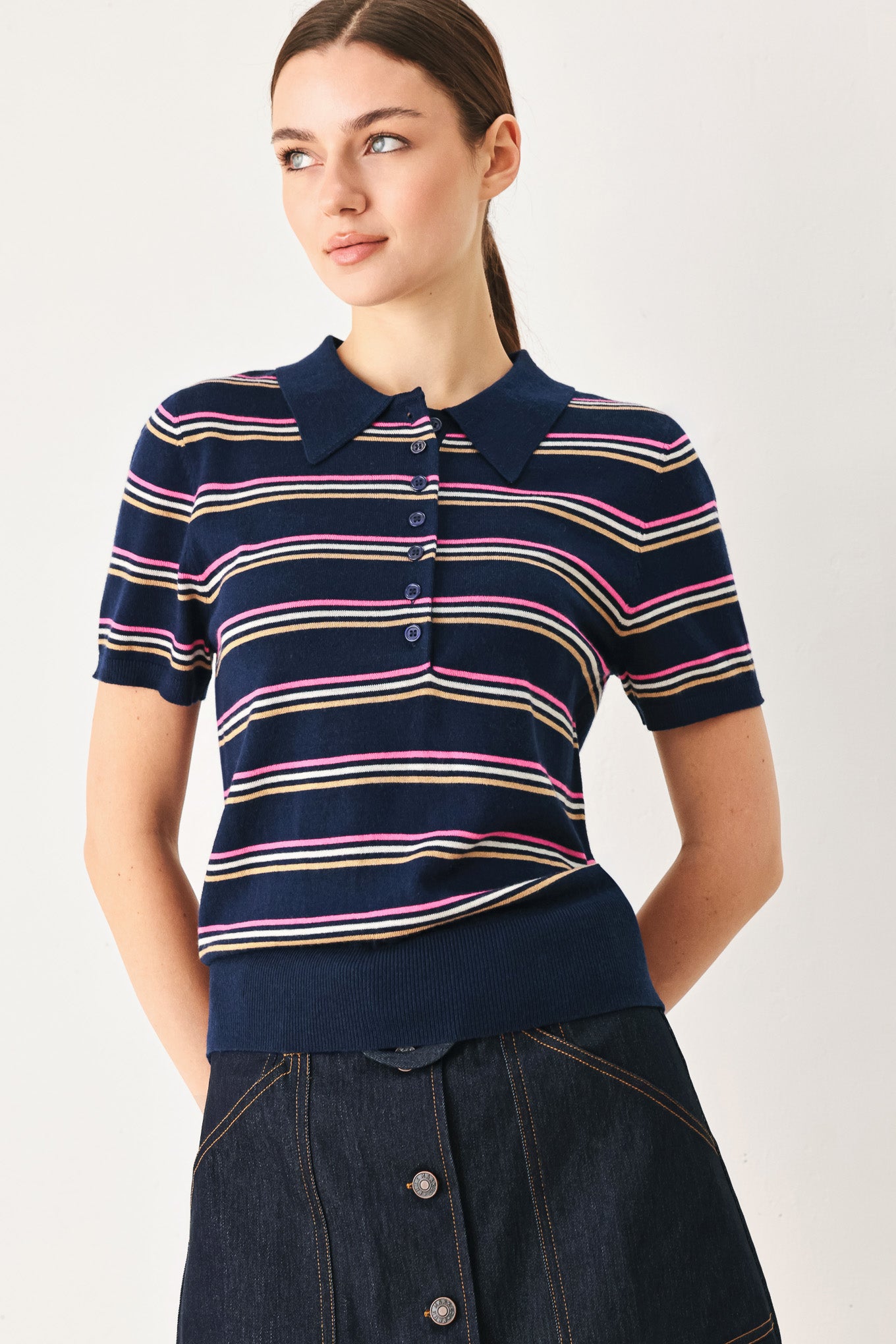 A woman wearing a navy blue short-sleeve polo shirt with thin horizontal stripes in pink, yellow, and white | FREEMARKET