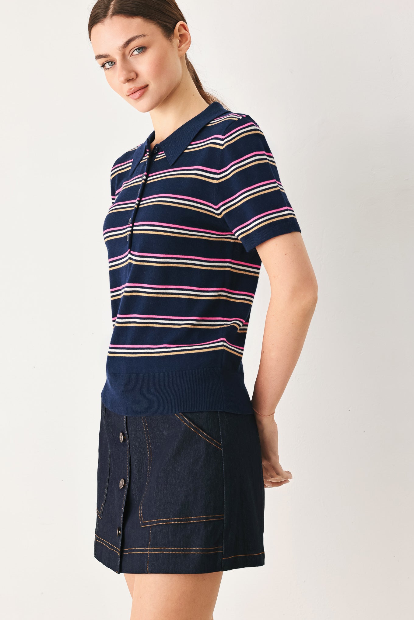 A woman wearing a navy blue short-sleeve polo shirt with thin horizontal stripes in pink, yellow, and white | FREEMARKET