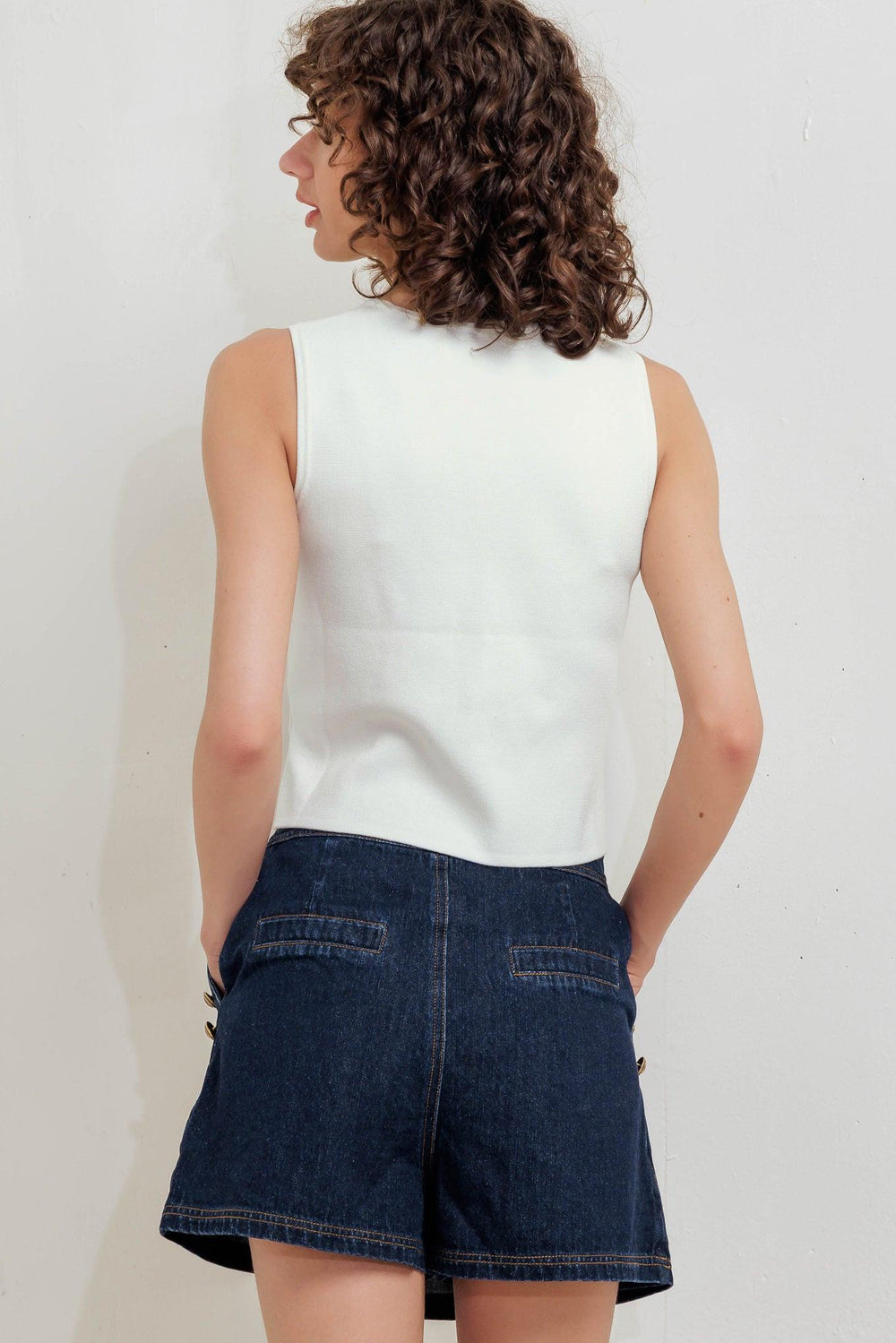 A solid white sweater vest with front button closure