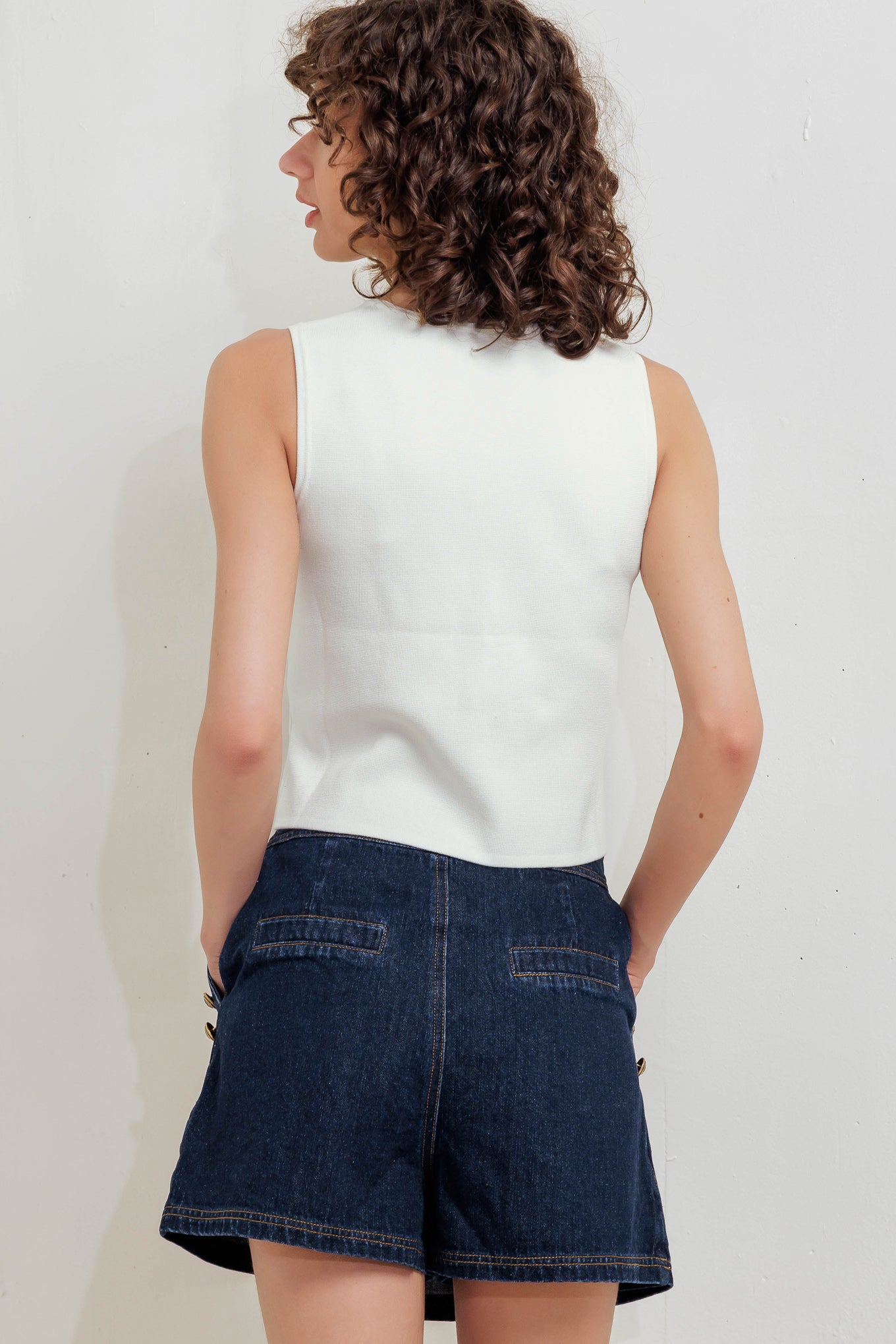 A solid white sweater vest with front button closure