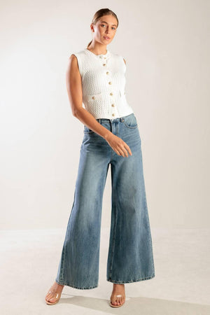 A white, sleeveless, sweater knit vest featuring round neckline and button down closure.