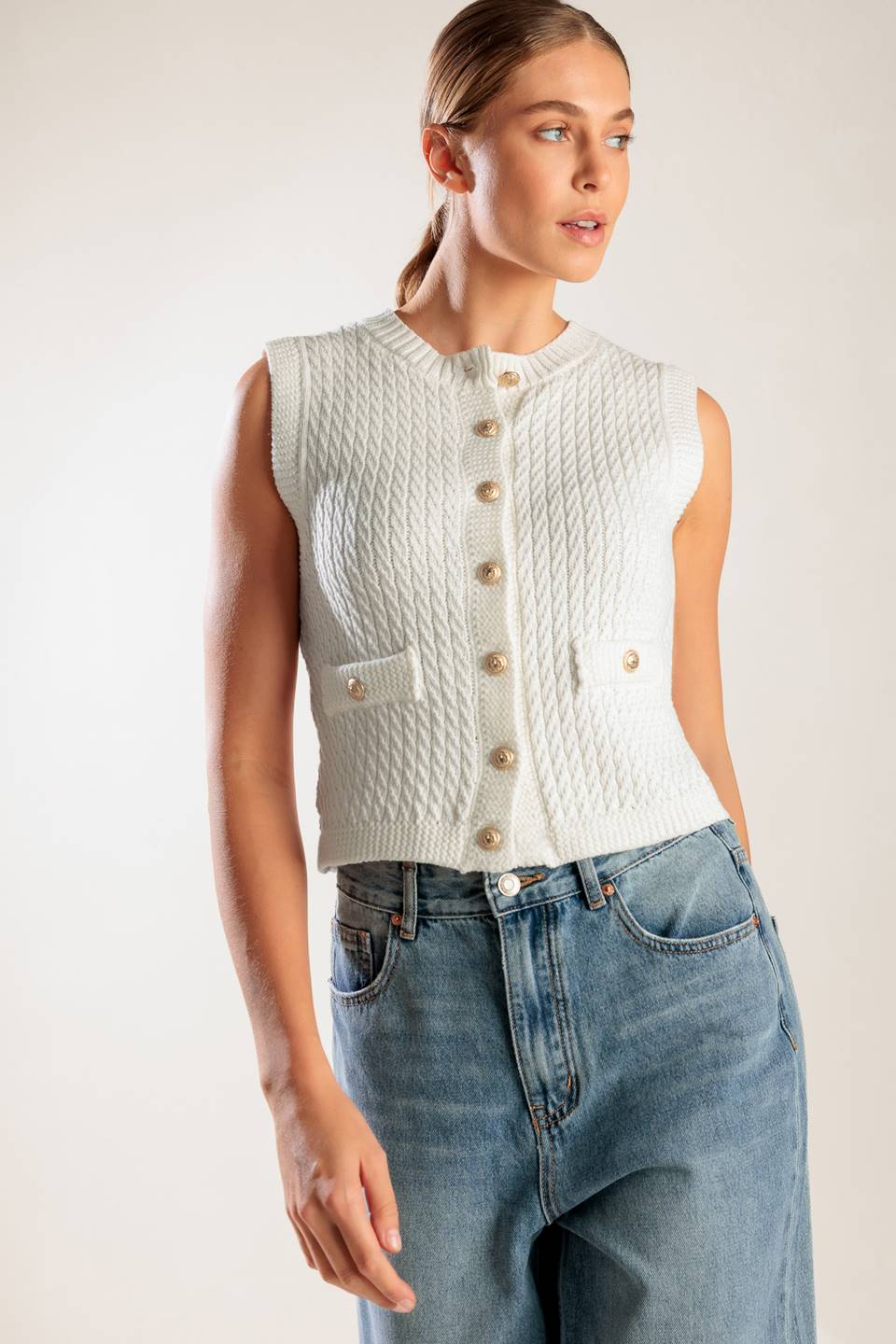 A white, sleeveless, sweater knit vest featuring round neckline and button down closure.