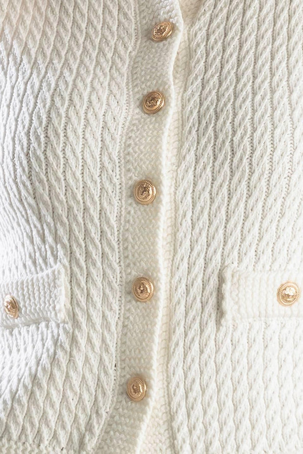 A white, sleeveless, sweater knit vest featuring round neckline and button down closure.