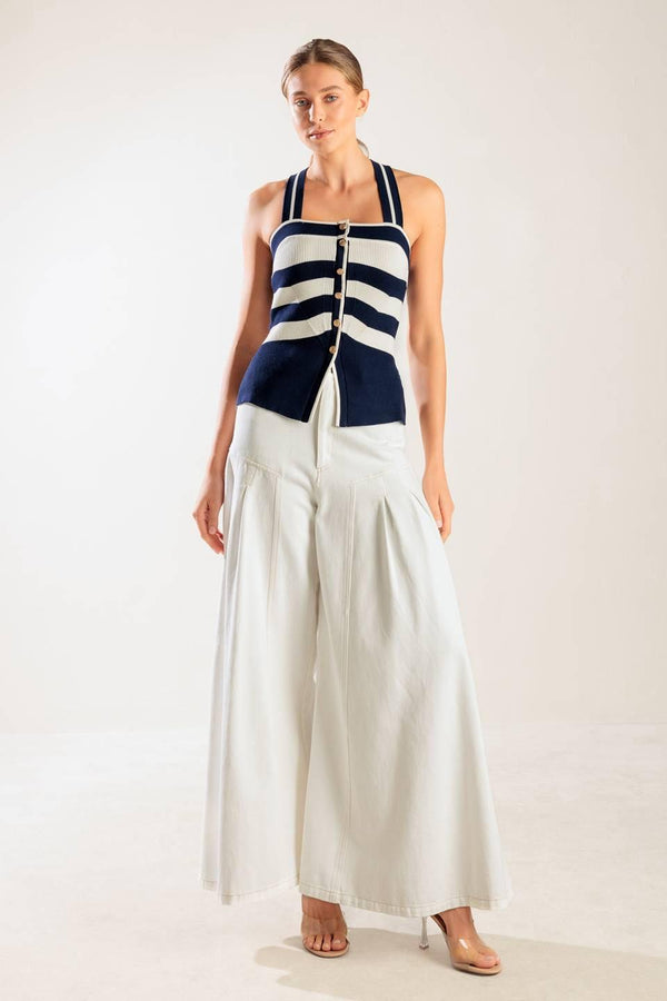 A navy and white striped sweater knit top featuring a halter neckline button down closure and cross back strap.