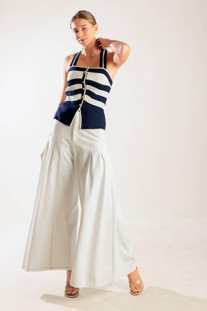 A navy and white striped sweater knit top featuring a halter neckline button down closure and cross back strap.