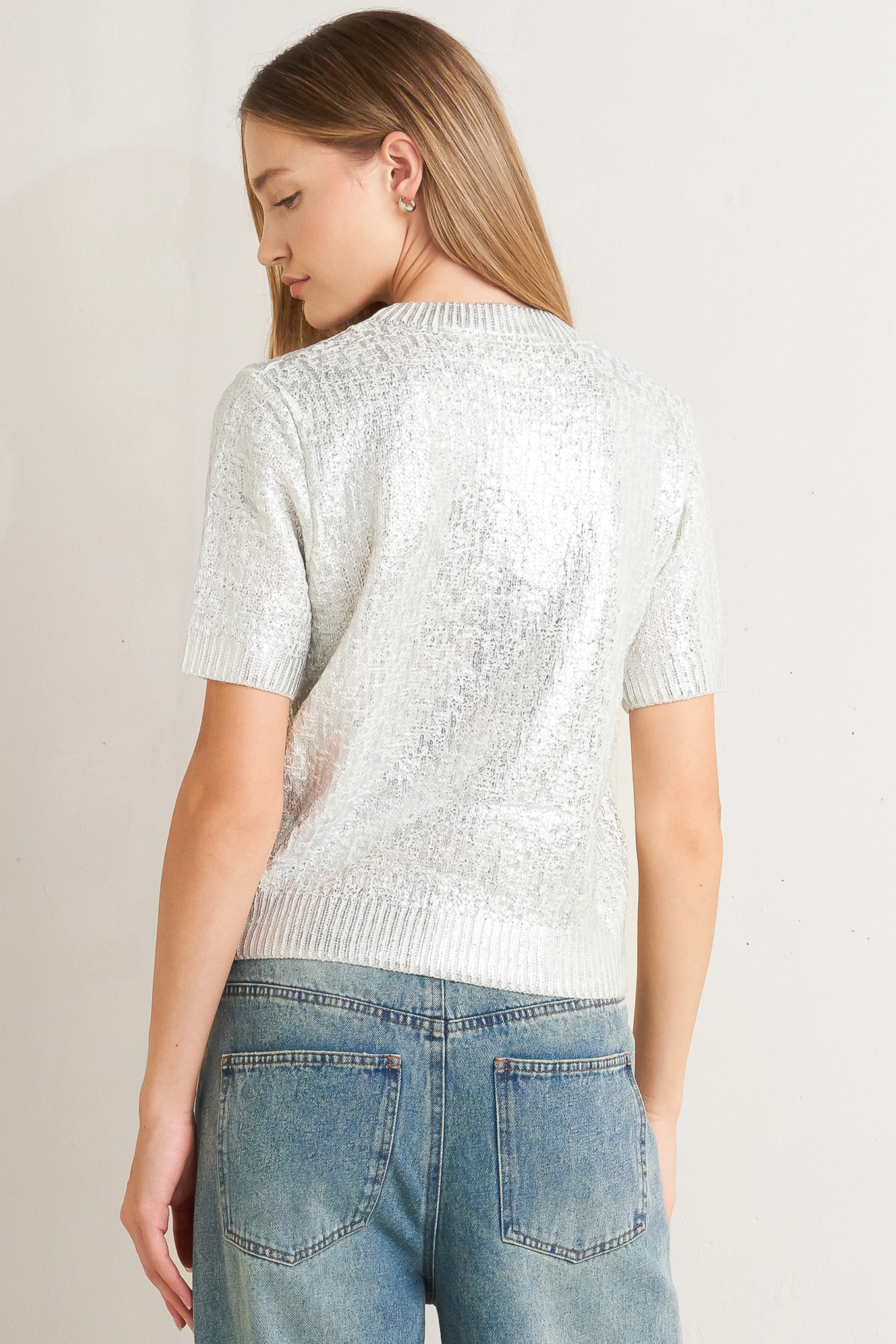 A foiled sweater knit top featuring crew neckline and short sleeve