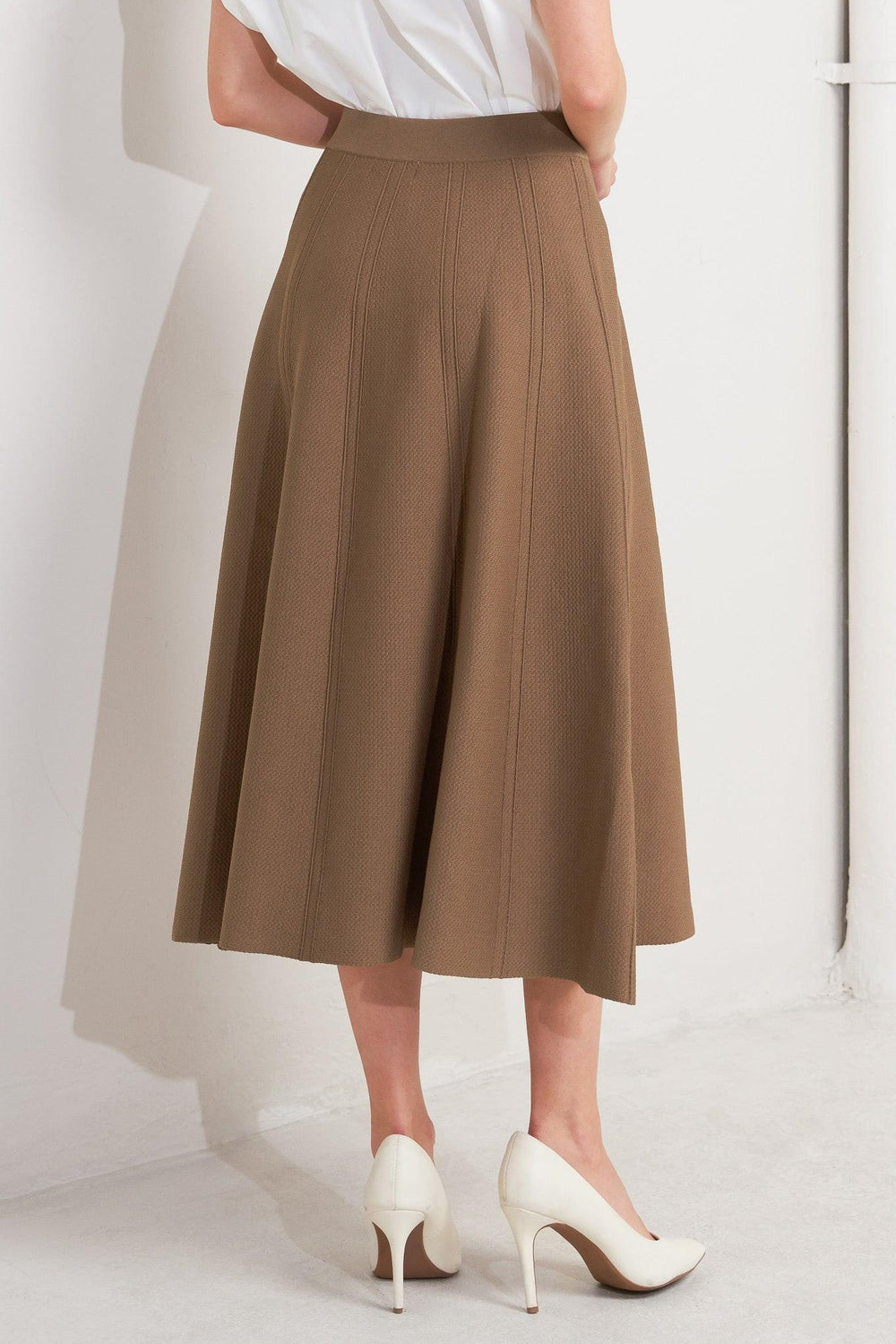 Person wearing a brown skirt and white shoes on a white background - Flying Tomato