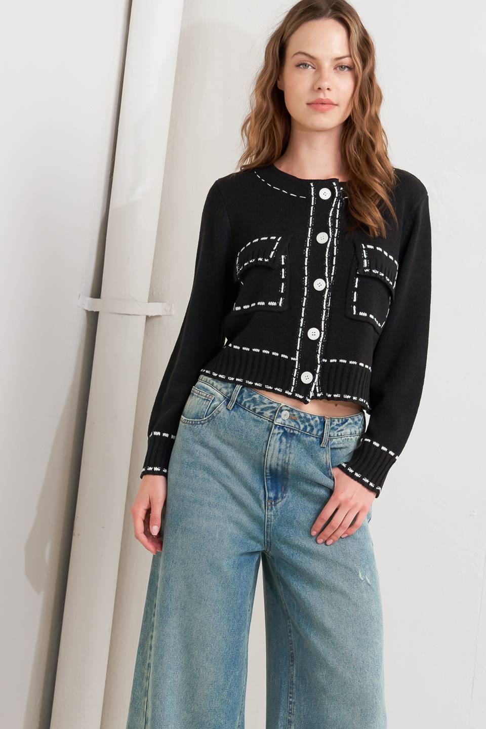 A sweater knit top featuring round neckline, button down, long sleeve and stitch edge detail