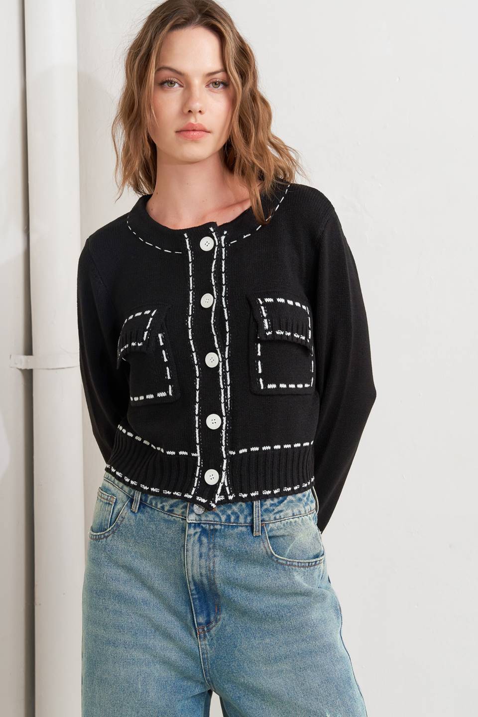A sweater knit top featuring round neckline, button down, long sleeve and stitch edge detail