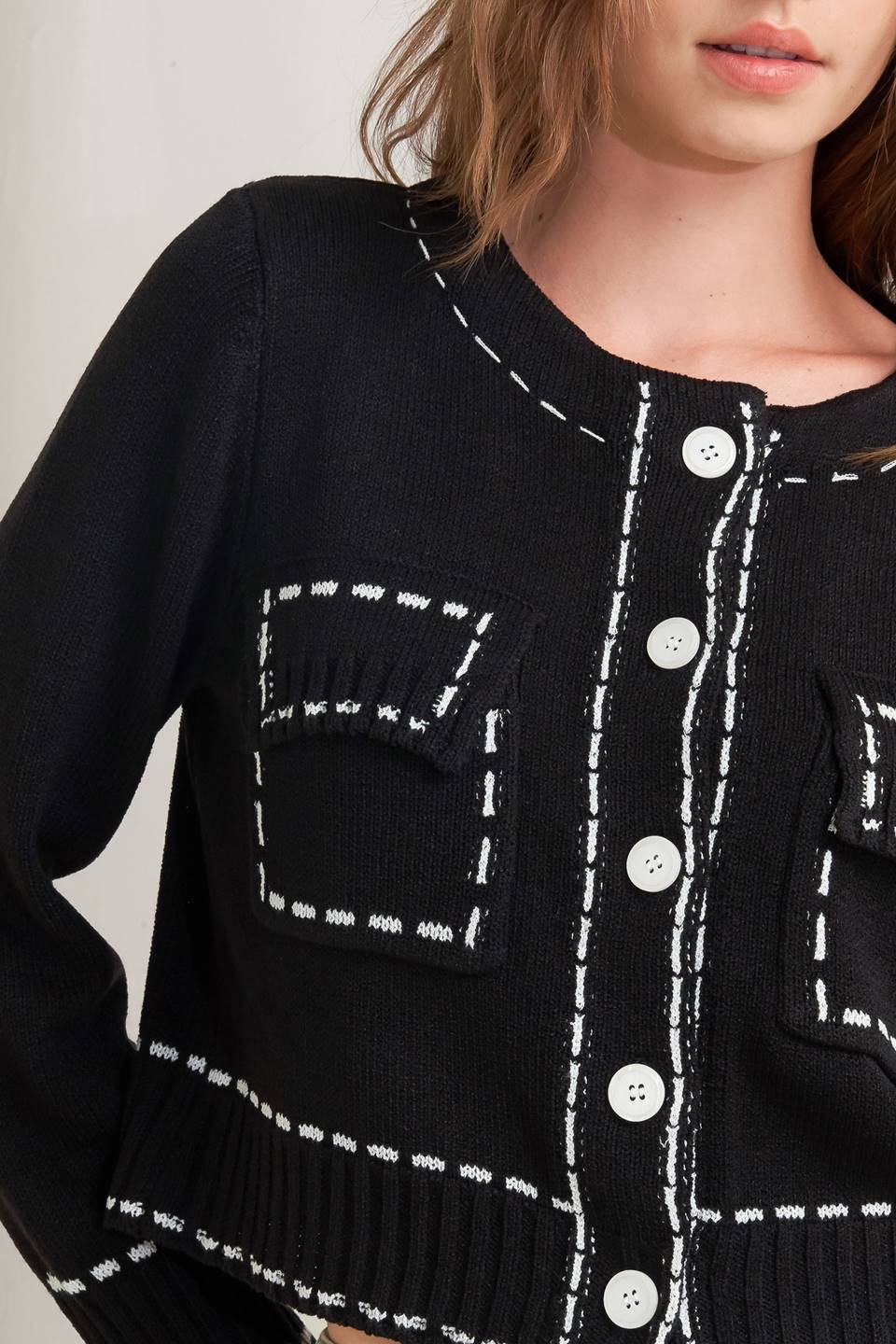 A sweater knit top featuring round neckline, button down, long sleeve and stitch edge detail