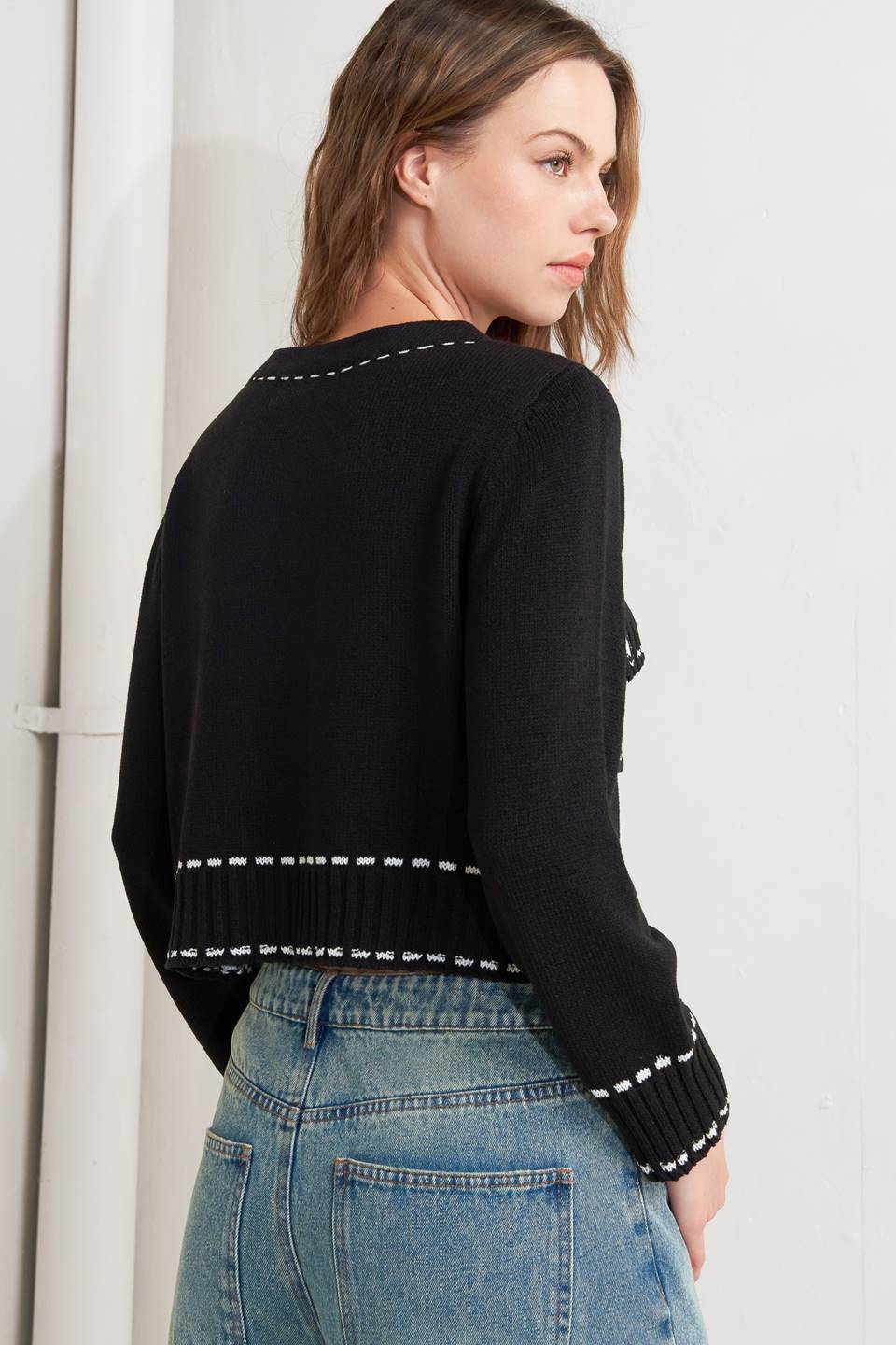 A sweater knit top featuring round neckline, button down, long sleeve and stitch edge detail