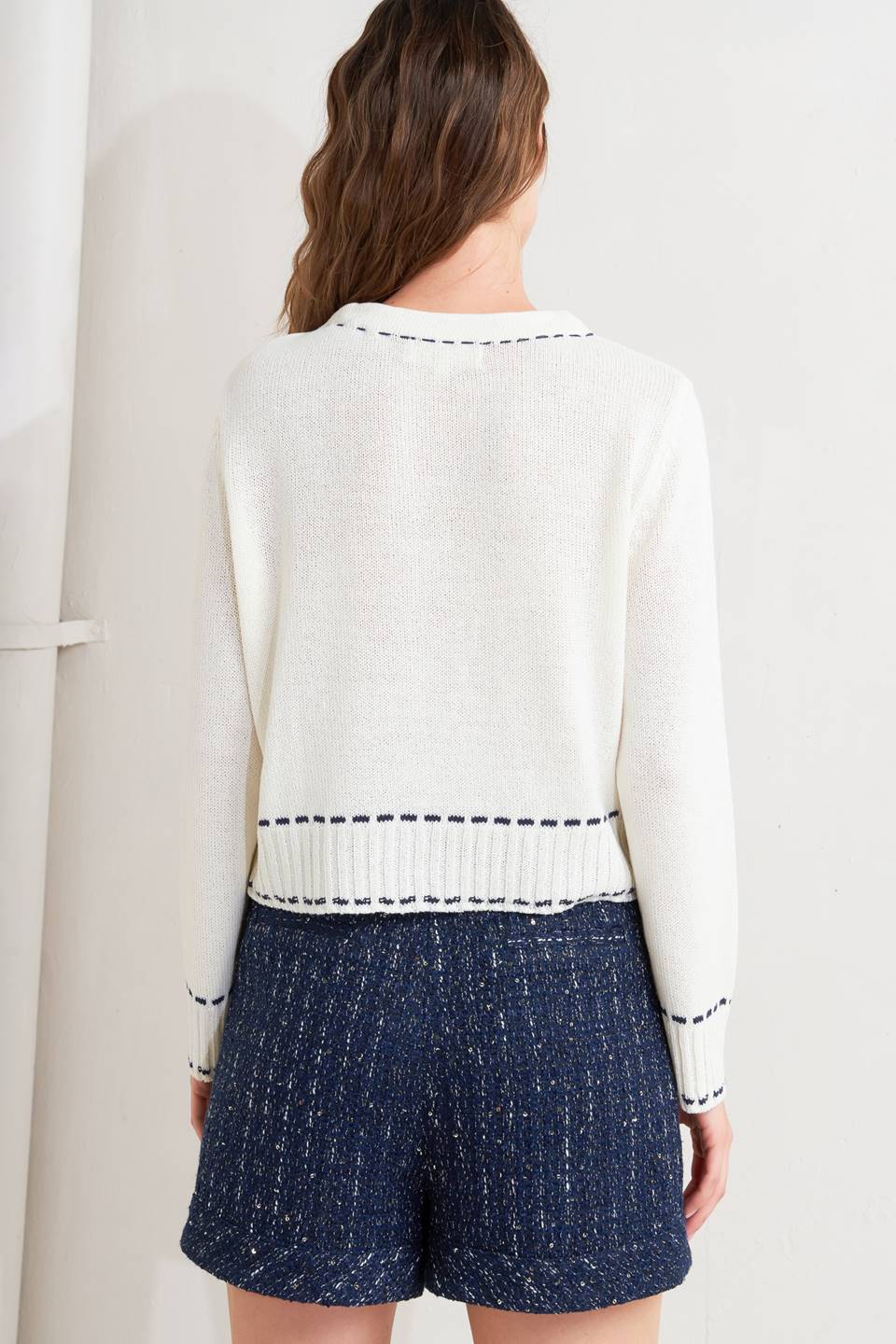 A sweater knit top featuring round neckline, button down, long sleeve and stitch edge detail