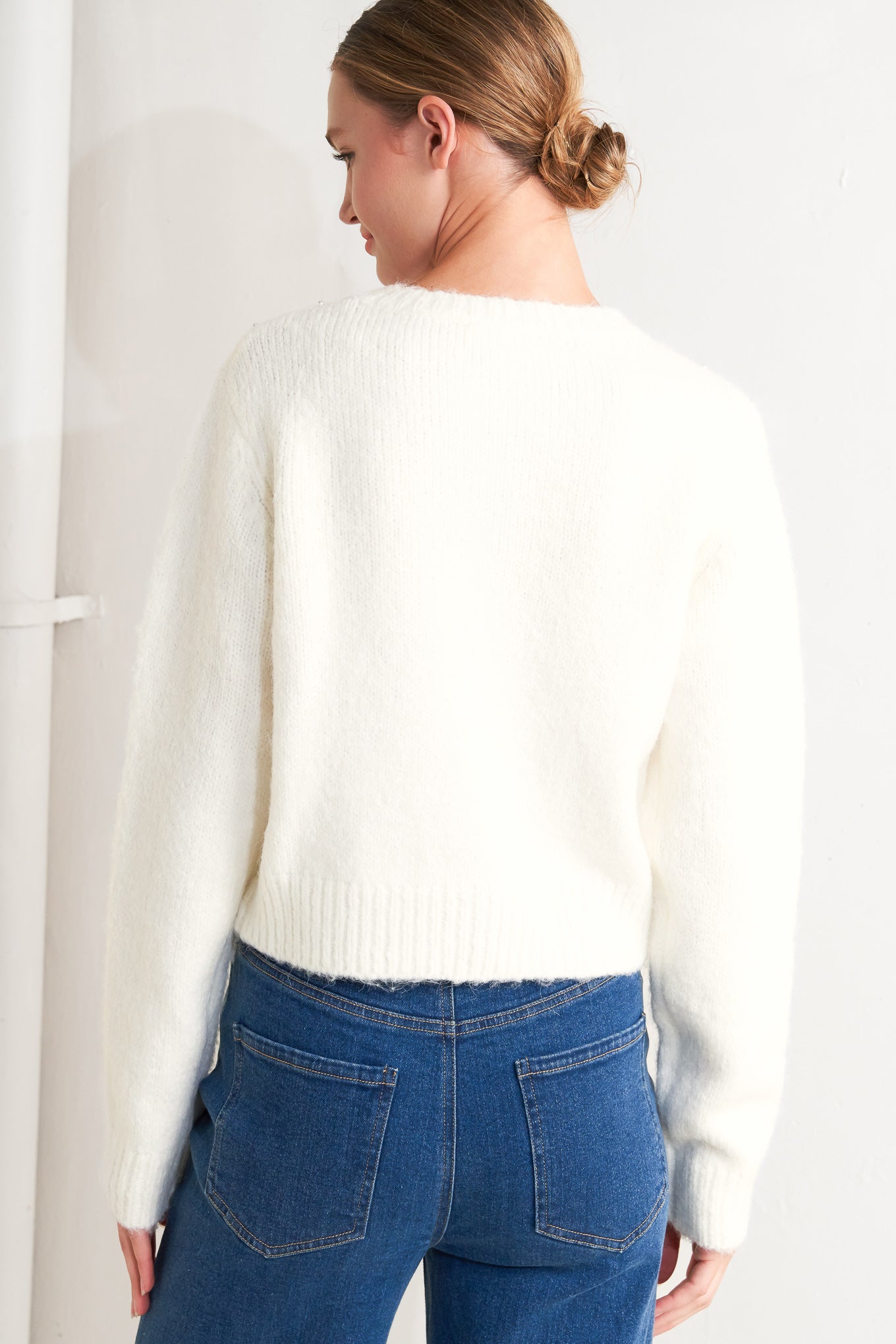 A sweater knit cardigan featuring round neckline, long sleeve and jewel embellishment and button