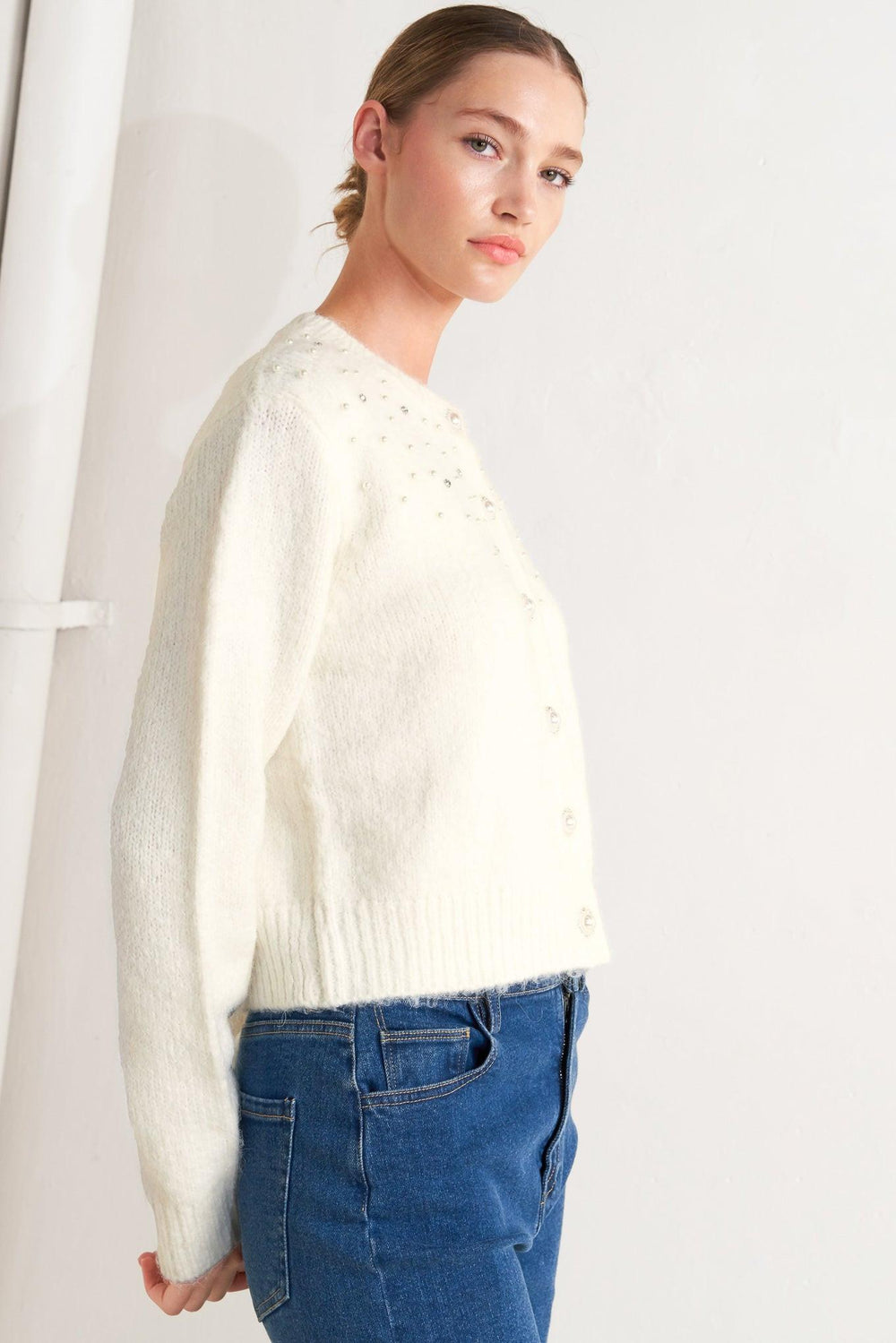 A sweater knit cardigan featuring round neckline, long sleeve and jewel embellishment and button