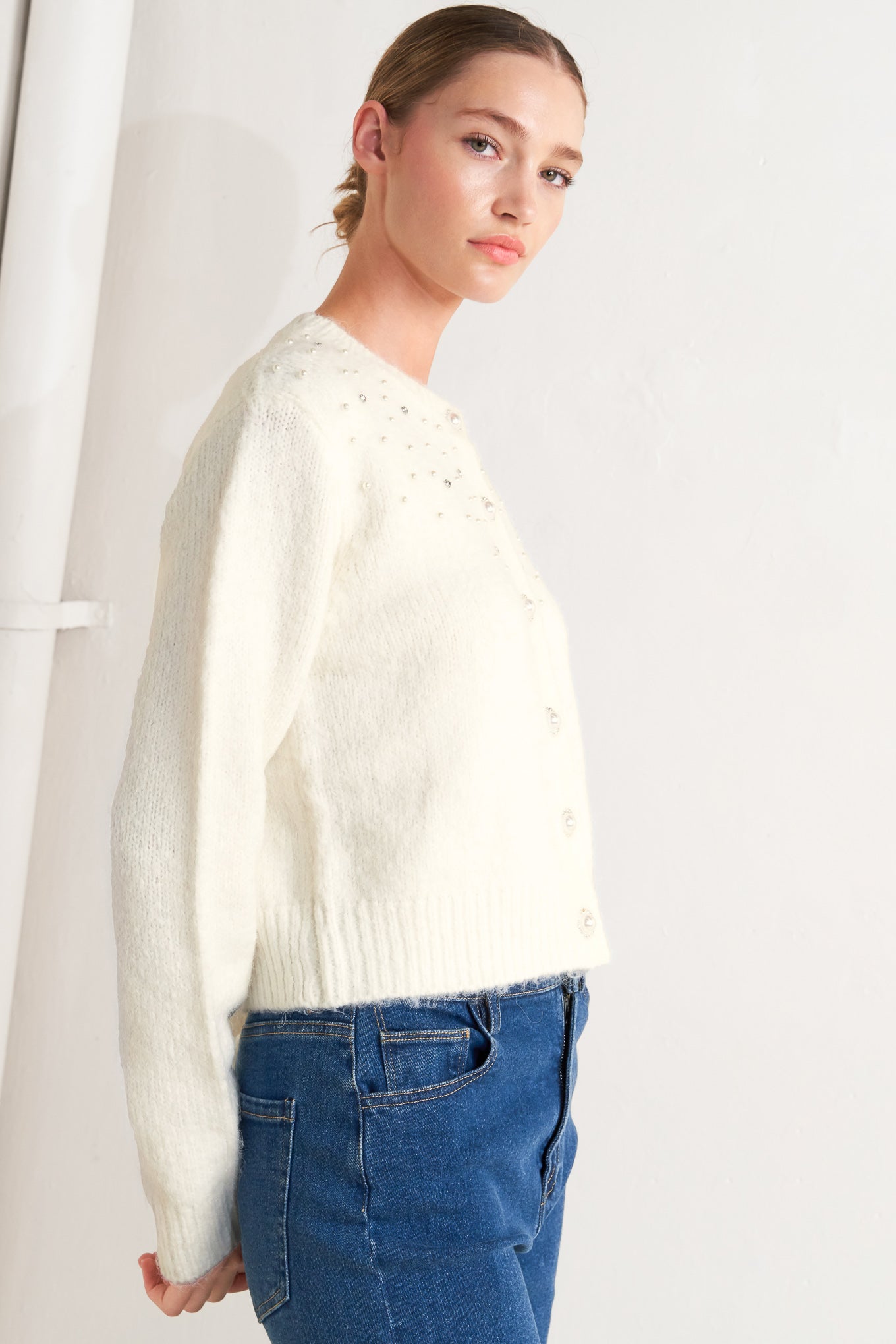 A sweater knit cardigan featuring round neckline, long sleeve and jewel embellishment and button