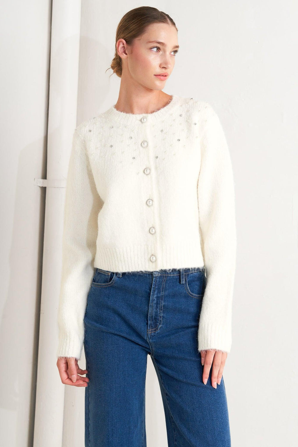 A sweater knit cardigan featuring round neckline, long sleeve and jewel embellishment and button