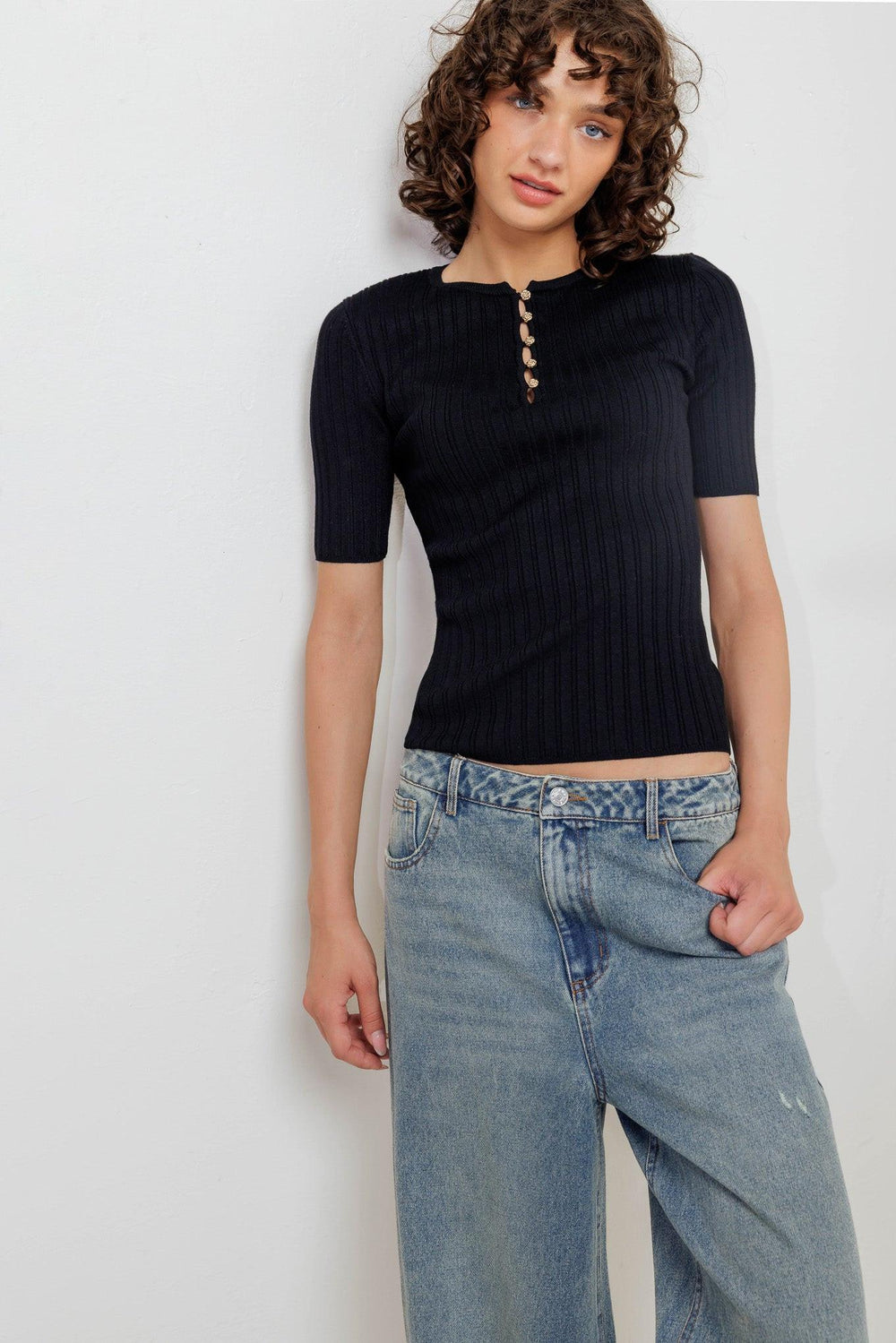 A ribbed sweater knit top featuring round neckline, front button closure and short sleeve