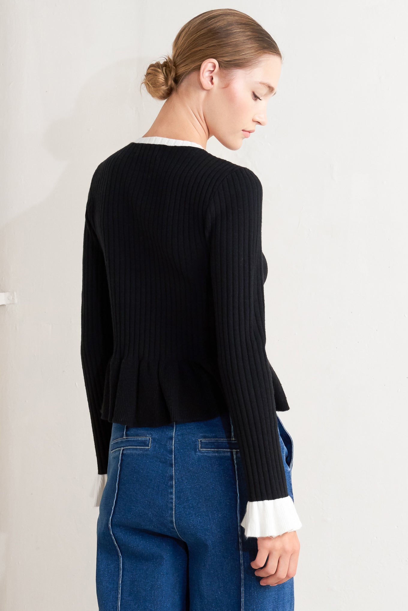 A sweater knit top featuring round neckline, long sleeve with ruffled sleeve and ruffled peplum