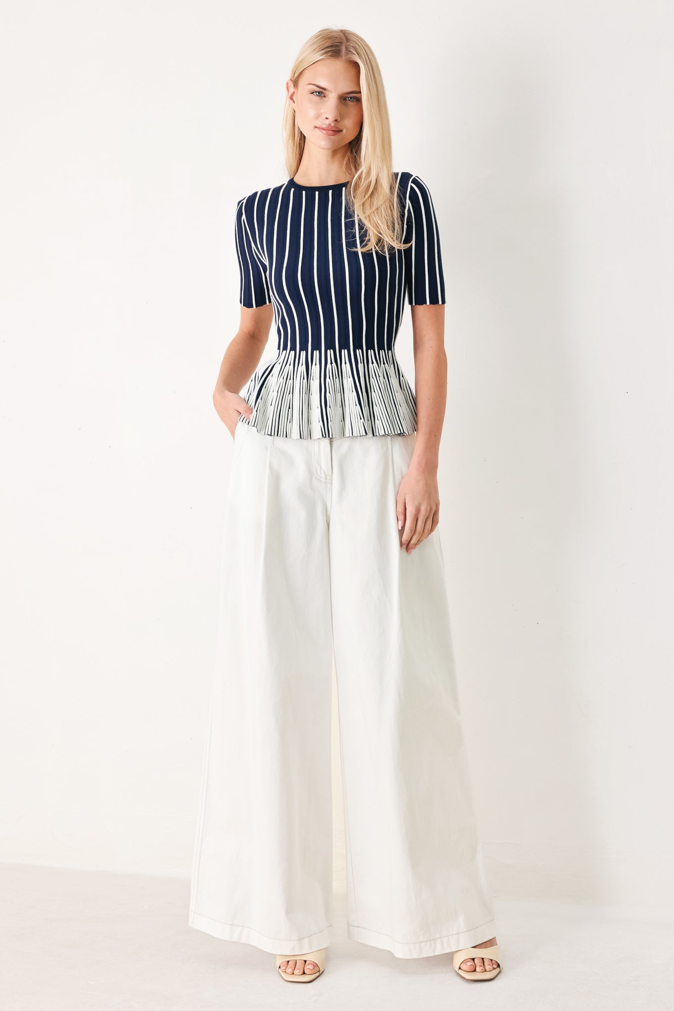 Woman wearing a navy and white striped sweater knit top with a peplum waist | FREEMARKET